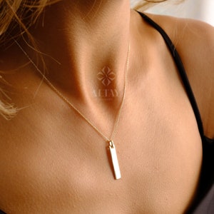 May include: A gold chain necklace with a thin, rectangular pendant. The pendant is smooth and has a polished finish.