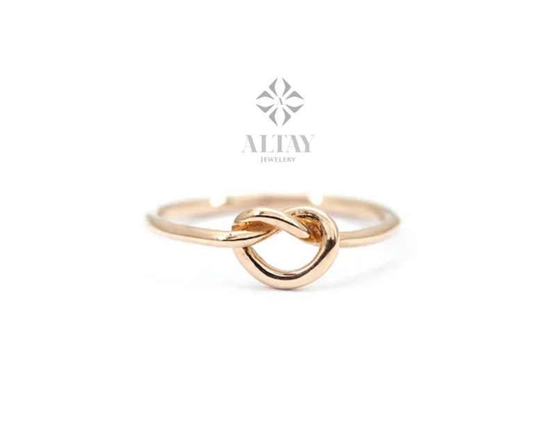 Op de afbeelding: Een gouden knoop ring met een eenvoudig ontwerp. De ring is gemaakt van glad, gepolijst metaal en heeft een klassieke, tijdloze uitstraling.