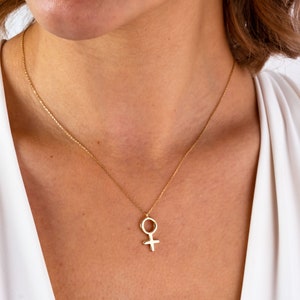 K&ouml;nnte beinhalten: Eine goldene Halskette mit einer zarten Kette und einem Anh&auml;nger in Form des weiblichen Symbols.