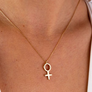 K&ouml;nnte beinhalten: Eine goldene Kettenkette mit einem schlichten, minimalistischen Anh&auml;nger in Form des weiblichen Symbols.