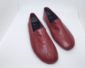 May include: A pair of red leather slippers with a pointed toe and a simple design.