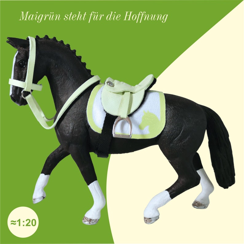 Ein schwarzes Schleich Pferd mit einemhellgrünen Sattel und einer Trense. Darüber steht der Schriftzug: Maigrün steht für die Hoffnung.