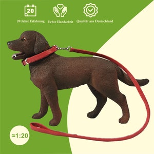 Ein dunkelbrauner Spielzeughund trägt ein rotes Halsband mit einer Leine.