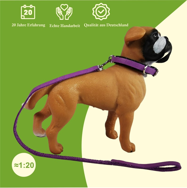 Ein junger Schleich Hund von der Seite, trägt ein Halsband in Violett. An dem Halsband ist eine Leine befestigt. Der Hund ist ein Boxer.