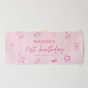 May include: A pink banner with the text "MADDIE'S 21st birthday" and "MIAMI, FLORIDA - 2026" in a cursive font. The banner is decorated with pink illustrations of a palm tree, champagne bottle, sunglasses, and other party-themed graphics.
