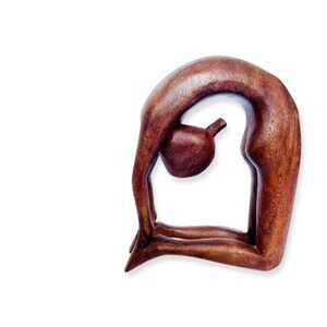 Puede incluir: Una escultura de madera de una persona en una postura de yoga. La escultura es de color marrón y tiene un acabado liso.