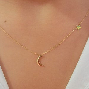 May include: A gold chain necklace with a crescent moon charm and a star charm