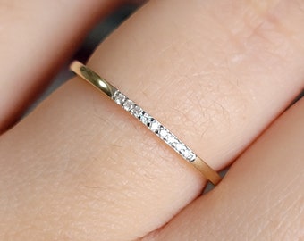 May include: A delicate gold band ring with a row of small diamonds set along the top.