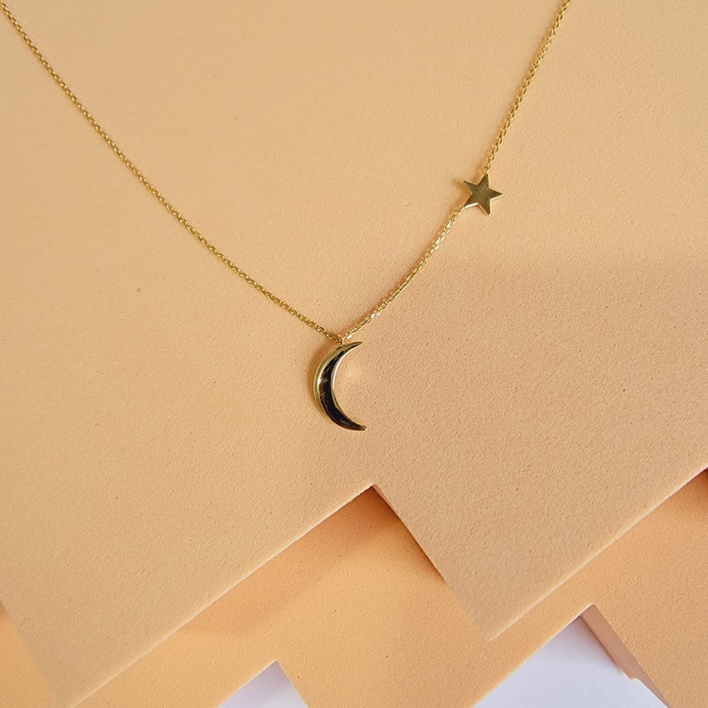 May include: A gold necklace with a crescent moon pendant and a star charm.