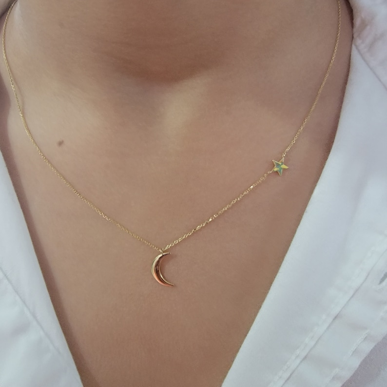 May include: A gold chain necklace with a crescent moon pendant and a small star charm.
