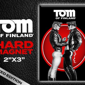 May include: A red and white hard magnet featuring two men in leather jackets. The magnet is 2 inches by 3 inches and has the text "TOM OF FINLAND" on it.