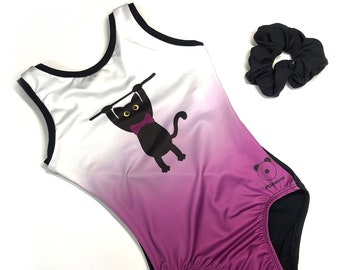 May include: White and purple ombre leotard with a black cat wearing a bow tie hanging from a bar. The leotard has a black trim and the brand name "Mimosa" is printed on the right side. A black scrunchie is included.