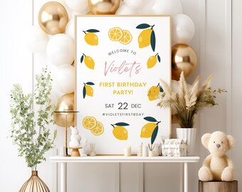 May include: A white sign with a yellow lemon theme for a first birthday party. The sign says "Welcome to Violet's First Birthday Party! Sat 22 Dec #violetsfirstbday".