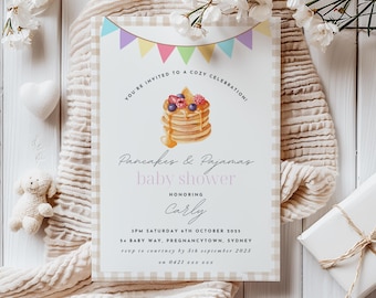 May include: A baby shower invitation with a pink and white gingham background. The invitation features a watercolor illustration of a stack of pancakes with blueberries, raspberries, and maple syrup. The text reads "You're invited to a cozy celebration/ Pancakes & Pajamas baby shower honoring Carly/ 3PM Saturday 6th October 2025/ 54 Baby Way, Pregnancytown, Sydney/ RSVP in courtesy by 5th September 2025/ on 0421 222 2222"