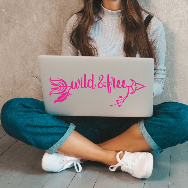 May include: A laptop computer with a pink arrow and feather design and the words "wild & free" on the lid.