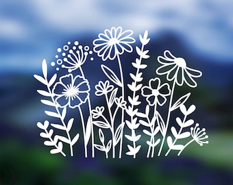May include: White line art of various wildflowers and foliage against a blurred blue and green background. The design features detailed outlines of daisies, other flowers, and leaves, creating a delicate, natural aesthetic.