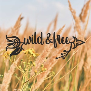 May include: A black arrow with the words "wild & free" written on it. The arrow is in front of a field of tall, brown grass with yellow flowers.
