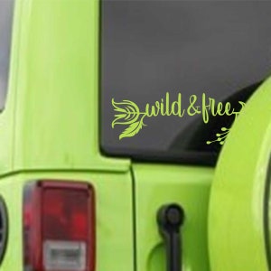 May include: A green car with a green vinyl decal on the back window. The decal features a stylized arrow with feathers and the text "wild & free".