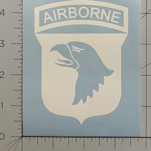 May include: White vinyl decal of the 101st Airborne Division patch. The patch features a white eagle head with a white arched banner above it that reads "AIRBORNE".