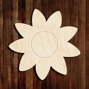 May include: A wooden cutout of a flower with ten petals and a circle in the center. The flower is light brown and has a natural wood grain.
