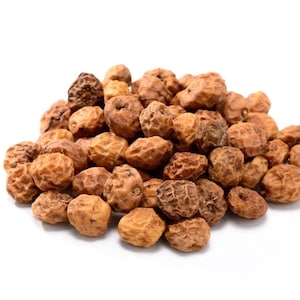 May include: A pile of dried tiger nuts, also known as chufa, featuring a wrinkled, light brown, and tan textured surface. Each small, round tuber displays a unique, irregular pattern of ridges and crevices across its firm, organic exterior.