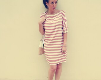 May include: A woman wearing a striped pink and white dress with a white bag and brown sandals.