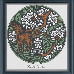 以下が含まれることがあります： 鹿と花が描かれた緑、白、茶色のマンホールの蓋。蓋の下に「奈良、日本」の文字がある。