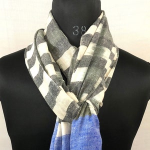 Può includere: Una sciarpa con un motivo a strisce bianche e grigie e una sezione blu tinta unita. La sciarpa è legata attorno a un manichino nero.