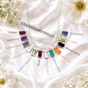 Puede incluir: Un collar de cadena de plata con múltiples dijes de piedras preciosas rectangulares de corte baguette etiquetados como granate, amatista, labradorita, piedra lunar arcoíris, peridoto, rubí, cuarzo rosa, ónix verde, cornalina, ónix negro, citrino y tanzanita.