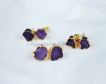 May include: Three pairs of gold-plated earrings with purple amethyst stones. The stones are irregularly shaped and have a natural, raw look.