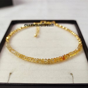 May include: A gold chain bracelet with a clasp closure, featuring a row of small, faceted, yellow citrine gemstones.