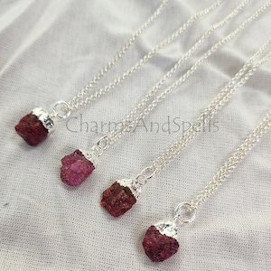 Peut inclure: Quatre colliers en argent avec des pendentifs en cristal de rubis brut. Chaque collier présente un cristal de rubis de taille différente, allant du petit au grand. Les cristaux sont d'une couleur rouge foncé et ont une texture naturelle et rugueuse.