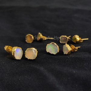 May include: A set of six gold-toned earrings with irregular shaped opal stones. The earrings are a mix of white and iridescent opals.