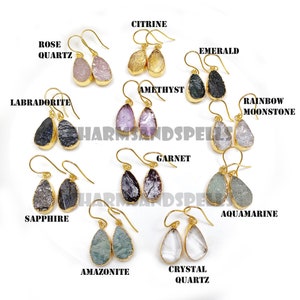 May include: A selection of gemstone earrings with gold settings. The earrings showcase diverse stones such as rose quartz, citrine, amethyst, emerald, and more. The text "HARMSANDSPELLS" is displayed.