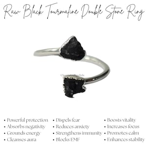 May include: A silver ring featuring two raw black tourmaline stones. The ring's band curves around the finger, with a stone at each end. The text "Raw Black Tourmaline Double Stone Ring" is at the top. The ring is from CharmsAndSpellsIn.