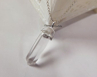 May include: A clear quartz crystal pendant on a silver chain. The pendant is shaped like a point and has a silver bail. The chain is delicate and has a lobster clasp. The pendant is approximately 5 cm long.