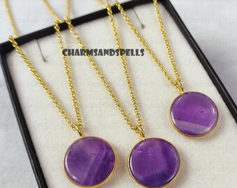 May include: Three gold chains with amethyst stone pendants. The pendants are round and have a smooth, polished finish. The chains are delicate and have a classic design.