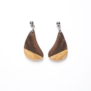 May include: A pair of wooden earrings with a dark brown and light brown wood design. The earrings are shaped like a teardrop and have a silver metal hook.