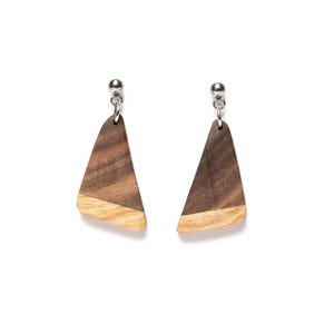 May include: A pair of wooden earrings with a triangular shape. The earrings are made of two different types of wood, one dark brown and one light brown. The earrings have silver posts.
