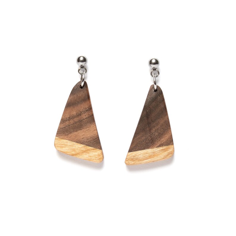 May include: A pair of wooden earrings with a triangular shape. The earrings are made of two different types of wood, one dark brown and one light brown. The earrings have silver posts.