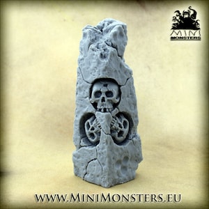Könnte beinhalten: Eine graue, verwitterte Steinskulptur mit einem Schädel und einem Skelettkäfig-Design. Die Skulptur hat ein rissiges, gealtertes Aussehen, mit dem Text "WWW.MINIMONSTERS.EU" am Sockel und einem Logo in der oberen rechten Ecke.