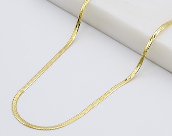 May include: A gold snake chain necklace with a delicate, textured design. The chain is displayed on a white surface.