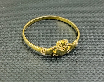May include: A gold-coloured ring featuring a Celtic knot design. The ring is made of metal and has a smooth finish.