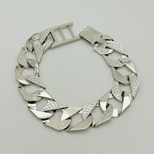 Peut inclure: Un bracelet en argent avec un motif texturé et un fermoir à ressort.