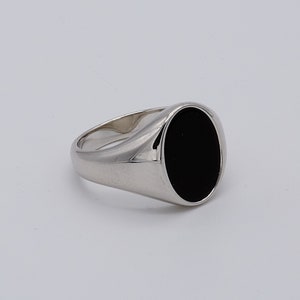 May include: A silver signet ring with a black oval gemstone.