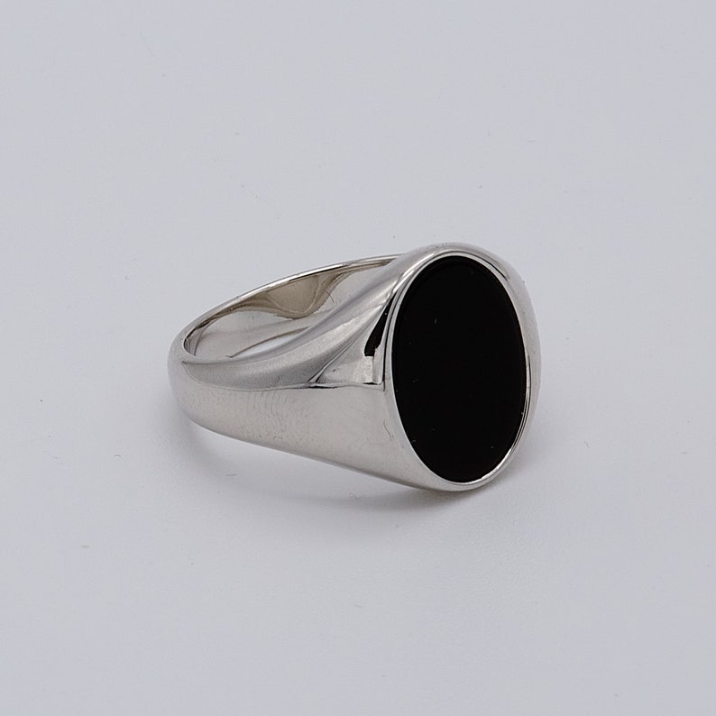 May include: A silver signet ring with a black oval gemstone.