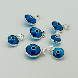 以下が含まれることがあります： 青いガラスの目をつけた銀製の邪視よけチャームが7つ。チャームは丸型で、吊り下げ用の銀のループが付いています。
