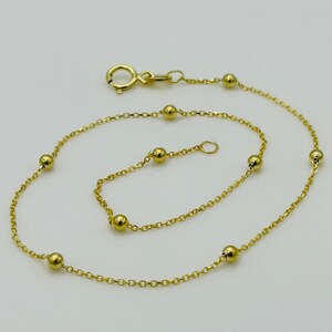 May include: A delicate gold chain anklet with small round beads. The anklet has a lobster clasp closure.