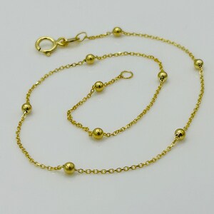 May include: A gold chain bracelet with small round beads. The bracelet has a lobster clasp closure.