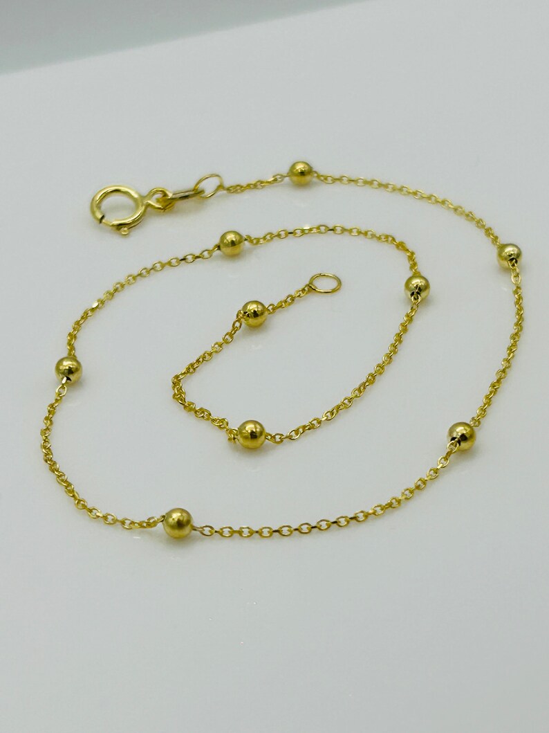 May include: A gold chain bracelet with small round beads. The bracelet has a lobster clasp closure.